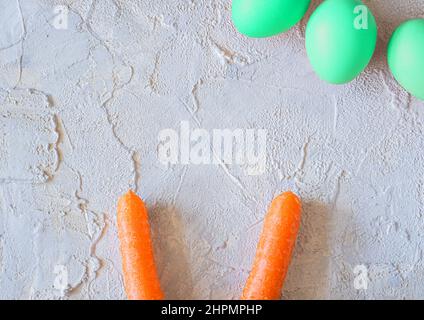 osterfarbene Eier mit Hasenohren auf hellem texturierten Hintergrund. Stockfoto