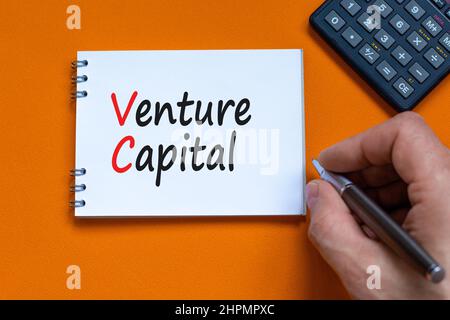 VC Venture Capital Abbrachfahrt Symbol. Konzept Wörter VC Venture Capital auf weißer Note. Businessman Hand, Rechner. Schöner orangefarbener Hintergrund. Cop Stockfoto