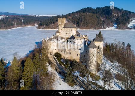 Polen. Mittelalterliche Burg in Niedzica, aus dem 14th. Jahrhundert (obere Burg) im Winter. Gefrorener künstlicher Czorsztyn-See auf dem Dunajec-Fluss Stockfoto