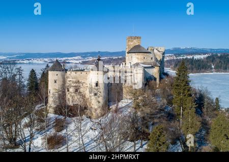 Polen. Mittelalterliche Burg in Niedzica, aus dem 14th. Jahrhundert (obere Burg) im Winter. Gefrorener künstlicher Czorsztyn-See auf dem Dunajec-Fluss. Stockfoto
