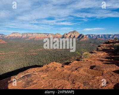 Riesige Aussicht von oben auf einem Berg neben einer Klippe mit Blick auf ein Tal, Felsformationen und andere Berge im frühen Abendlicht. Stockfoto