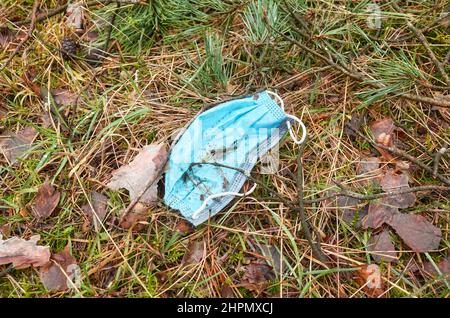 Weggeworfene medizinische Einweg-Gesichtsmaske im Wald, selektiver Fokus. Stockfoto