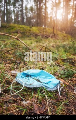 Nahaufnahme einer weggeworfenen medizinischen Einweg-Gesichtsmaske im Wald, selektiver Fokus. Stockfoto