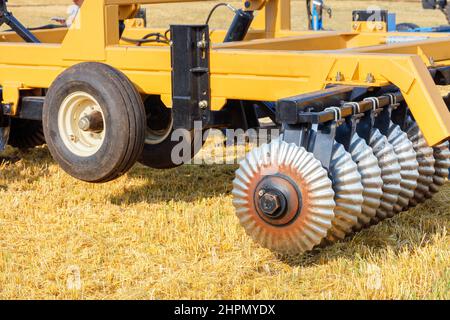 Ein Fragment einer gewellten Scheibenegge als Anhängerkupplung für die Bodenbearbeitung bei Feldarbeiten an einem landwirtschaftlichen Traktor. Nahaufnahme, Kopierbereich. Stockfoto