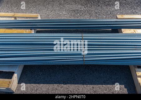 Horizontaler Schuss von zwei Stahlstapeln auf Holzpaletten auf einer neuen kommerziellen Baustelle. Stockfoto