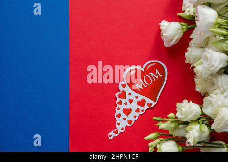 Happy Mother's Day Grußkarte mit Frühlingsblumen und dekorativem Herz auf rot-blauem Hintergrund.Design-Konzept - Draufsicht auf Strauß schön Stockfoto
