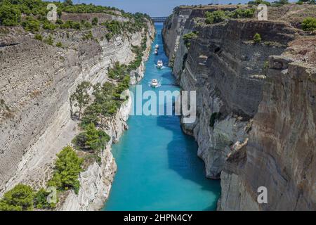 Die schöne Landschaft der Kanal von Korinth in einem hellen, sonnigen Tag gegen ein blauer Himmel mit weißen Wolken. Zwischen den Felsen fließenden weißen Schiff in Türkis wa Stockfoto