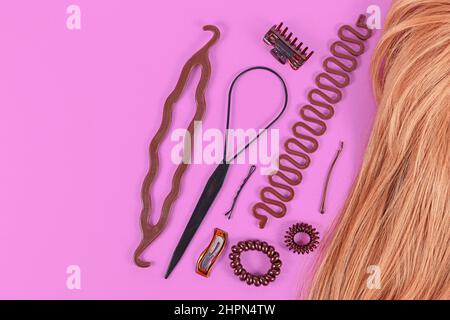 Set von Haar-Styling-Tools wie Bun Maker, Zopf-Werkzeug, Pferdeschwanz-Stil Maker, Haarclip, Gummibänder und Stifte neben blondem Haar mit Kopierraum Stockfoto