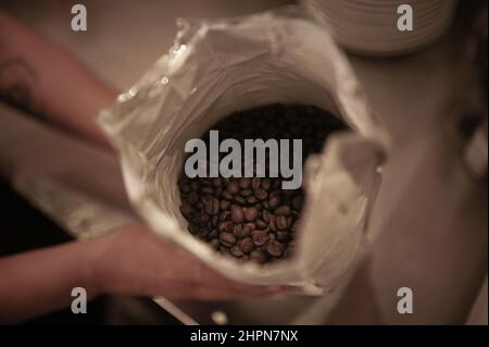 Rio De Janeiro, Brasilien. 22nd. Februar 2022. Der Mitarbeiter eines Cafés schüttelt eine Tüte Kaffeebohnen. Kredit: Andre Borges/dpa/Alamy Live Nachrichten Stockfoto