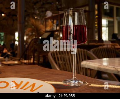 Ein Glas Rotwein auf einem Restauranttisch mit Beleuchtung im Glas und einem unscharfen Hintergrund. Stockfoto