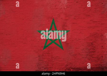 Full frame photo of a weathered flag of Morocco painted on a plastered brick wall. Stockfoto