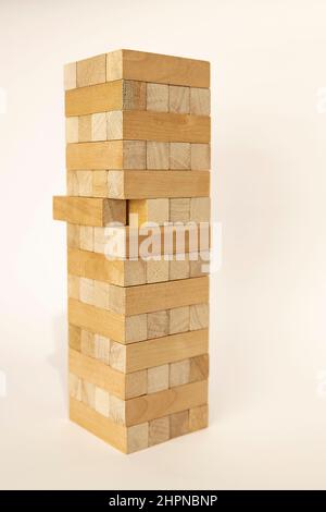 Nahaufnahme eines hellen Holzturms aus Blöcken. Ein Ziegel lag uneben. Brettspiel Jenga auf dem Tisch. Aktivität für Strategie und Konzentration. Unternehmen Stockfoto