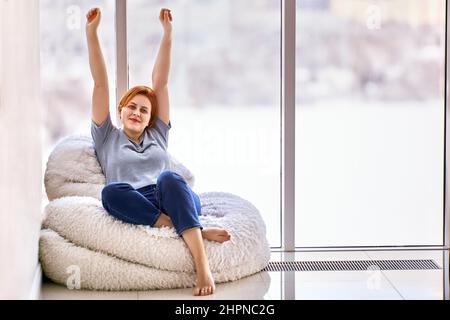 Hausbewaffnung in unmöblierter Wohnung von einer jungen Frau, die auf einem Stuhl sitzt. Stockfoto