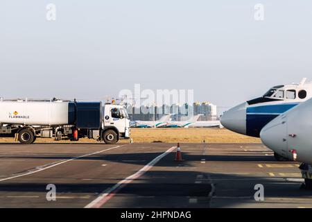 Seitenansicht kleiner moderner Tankwagen, der auf dem Rollweg des Flugplatzes zum Betanken von Flugzeugen fährt. Zisterne LKW Luftfahrt Benzin. Gasversorgung des Flugzeugs Stockfoto