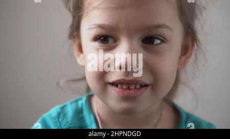 Portrait Lustige Happy Little Kid close up glücklich Vorschule Mädchen lächelnd Kind Blick auf die Kamera ziemlich natürliches Gesicht. Aufrichtige Emotionen beschämt Stockfoto