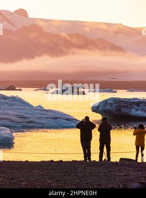 Eislagune. Silhouette von Touristen, die Fotos von der Eislagune des Sonnenuntergangs machen. Island Stockfoto