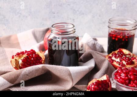 Gläser Granatapfelmelasse und frisches Obst auf hellem Hintergrund Stockfoto