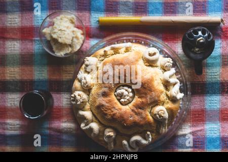 Der Familienvater hält die Feier des schutzpatrons Ein hausgemachtes Slava-Kuchenbrot von oben auf dem Tisch, um traditionelle Gerichte zu feiern, die für einen orthodoxen Urlaub zubereitet werden Stockfoto