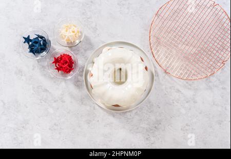 Flach liegend. Lasuring frisch gebackenen Bundt Kuchen mit Vanille-Glasur. Stockfoto