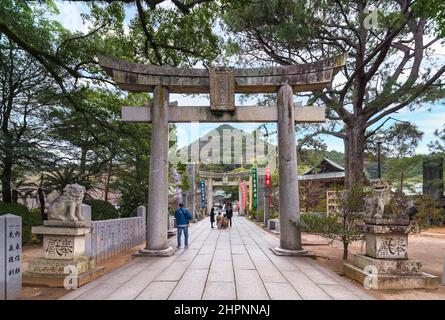 kyushu, japan - 08 2021. dezember: Japanische Familie auf dem sandō-Pfad des Miyajidake-Schreins, der von Torii-Portalen übersehen wird und von Komainu guardi umgeben ist Stockfoto