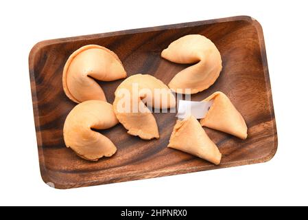 Ein Teller voller Glücksplätzchen, isoliert auf Weiß, einer davon mit Glücksgezeigezeichen aufgebrochen. Stockfoto