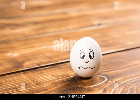 Nahaufnahme eines Eies mit einem lustigen Gesicht auf einer hölzernen Oberfläche Stockfoto