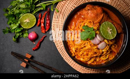 Traditionelle nordthailändische Küche. Khao Soi Kai, Nördliche Thai-Nudeln mit cremig-würziger gelber Suppe und Hühnerdrumstick. Stockfoto