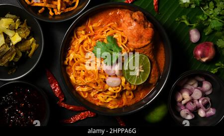 Leckere Khao Soi Kai, würzige gelbe Kurrysuppe mit Eiernudeln und Huhn serviert mit Beilage. Nordthailändische Küche. Stockfoto