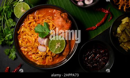 Würziger Khao Soi Kai, cremiges und leicht würziges gelbes Kerri mit Hähnchendrumstick. Draufsicht, nordthailändisches Küchenkonzept. Stockfoto