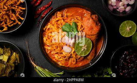 Leckeres nordthailändisches Speisekonzept, Khao Soi Kai oder cremiges und leicht würziges gelbes, mit Hähnchendrumstick und Eiernudeln serviertes, gelbes Kerrfleisch. Thailändisches Restaurant Stockfoto