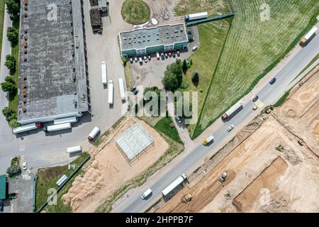 Lagerhäuser oder Logistikzentrum Ansicht von oben. Luftaufnahme von Industriegebäuden und LKWs mit Lastenaufliegern. Stockfoto