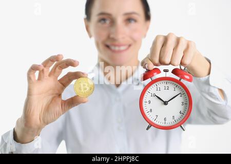 Frau hält goldene Bitcoin und Wecker Stockfoto