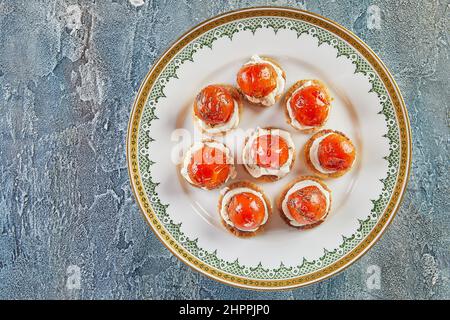 Snacks mit Ricotta-Käse und Kirschtomaten auf weißem Vintage-Teller. Französische Gourmetküche Stockfoto