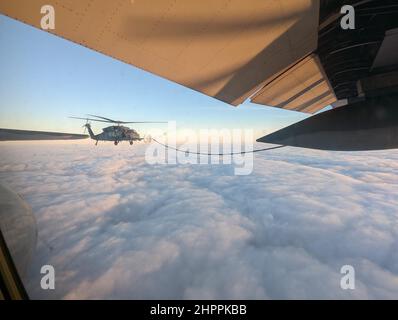 Ein Hubschrauber der US Air Force HH-60G Pave Hawk vom 129th Rettungsflügel fliegt während einer Rettungsmission 345 Seemeilen von San Francisco, 11. Februar 2022, mit einem HC-130J Combat King II zurück. Das Flugzeugpaar führte regelmäßig Schulungen durch, um die Mission erfolgreich abzuschließen. (USA Foto der Air National Guard von Chief Master Sgt. Sean Moore) Stockfoto