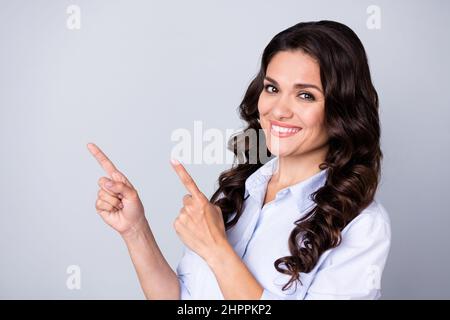 Foto von guten Brünette lockig reifen Dame zeigen leeren Raum tragen blaues Outfit isoliert auf grauem Hintergrund Stockfoto