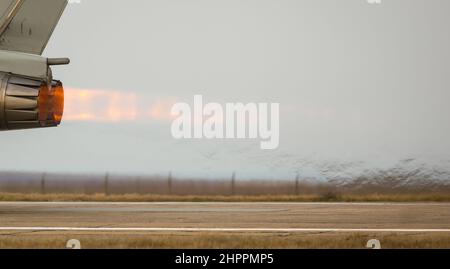 Details mit den Abgasen eines militärischen Düsenjägerflugzeugs beim Start von einem asphaltierten Rollweg. Stockfoto
