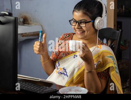 Indische Frau in Saree arbeiten am Computer und Tee zu Hause, Arbeit von zu Hause Konzept Stockfoto