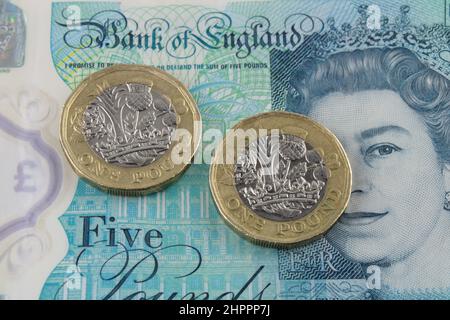 Britische Pfund-Münzen auf einem fünf-Pfund-Scheine Hintergrund. Wirtschaft, Verschuldung und Rezessionskonzept. Stockfoto