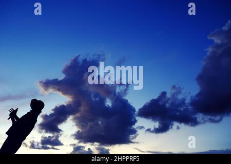 Lustige Szene bei Sonnenuntergang, wenn die Silhouette einer vietnamesischen Frau läuft, wenn die Tierform von der Wolkenjagd kommt, stellt sich die Frau auf dem Dach auf, wenn sie zu Hause in Gesellschaft bleibt Stockfoto