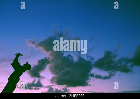 Lustige Szene bei Sonnenuntergang, wenn die Silhouette einer vietnamesischen Frau läuft, wenn die Tierform von der Wolkenjagd kommt, stellt sich die Frau auf dem Dach auf, wenn sie zu Hause in Gesellschaft bleibt Stockfoto