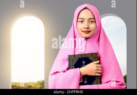 Asiatische muslimische Frau in einem Schleier stehend und den Koran auf der Moschee haltend Stockfoto