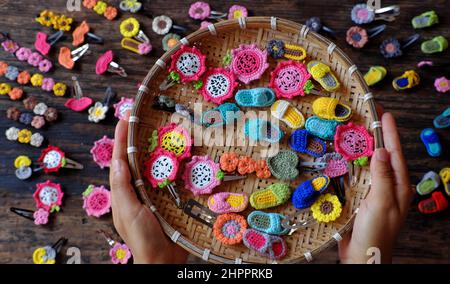 Draufsicht vietnamesische Frau Hand halten handgemachtes Produkt, Häkelhaarnadel in vielen Formen und bunte, hübsche Handarbeit Geschenk-Accessoires für die Schönheit auf bla Stockfoto