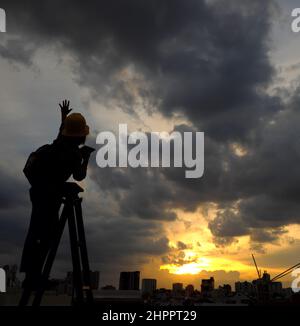 Erstaunliche Szene von vietnamesischen Frau, wenn zu Hause bleiben durch soziale Distanzierung, sie machen Spaß beim Sonnenuntergang auf dem Dach durch Stand auf Leiter, wenn die Sonne auf m untergehen Stockfoto