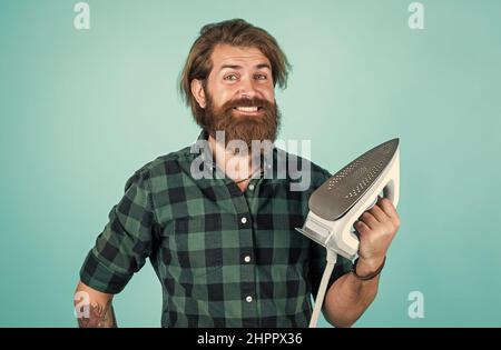 Nur einen Moment. Glückliche Verkäuferin im karierten Hemd. Bärtiger Mann. Neue Technologie. Reifer Hipster mit Bart verwenden dampfendes Eisen. Brutaler Kaukasier Stockfoto