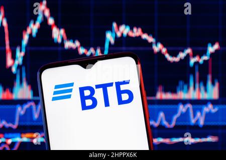 Smartphone mit VTB-Banklogo. VTB-Aktiendiagramm im Hintergrund. Stockfoto