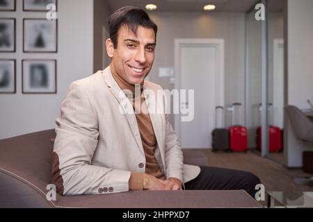 Fröhlicher Tourist, der in seinem Hotelzimmer sitzt Stockfoto