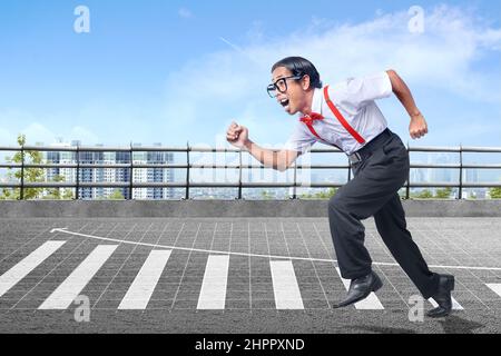 Asiatischer Nerd mit hässlichem Gesicht läuft mit erhöht Grafik auf dem Straßenhintergrund Stockfoto