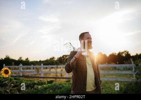 Glücklicher reifer Bauer Mann mit Gartenwerkzeug im Freien auf dem Feld. Stockfoto