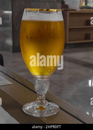 Ein frisches Glas gekühltes Bier wird auf einem Tisch serviert. Nahaufnahme. Stockfoto