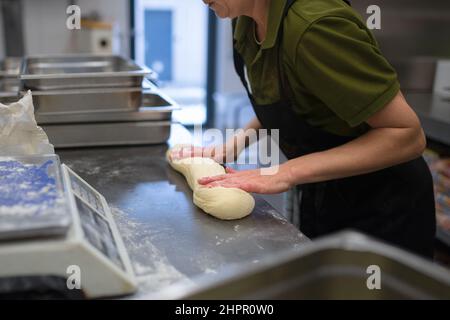 Nicht zu erkennender Koch knetet Hefeteig in der Restaurantküche. Stockfoto